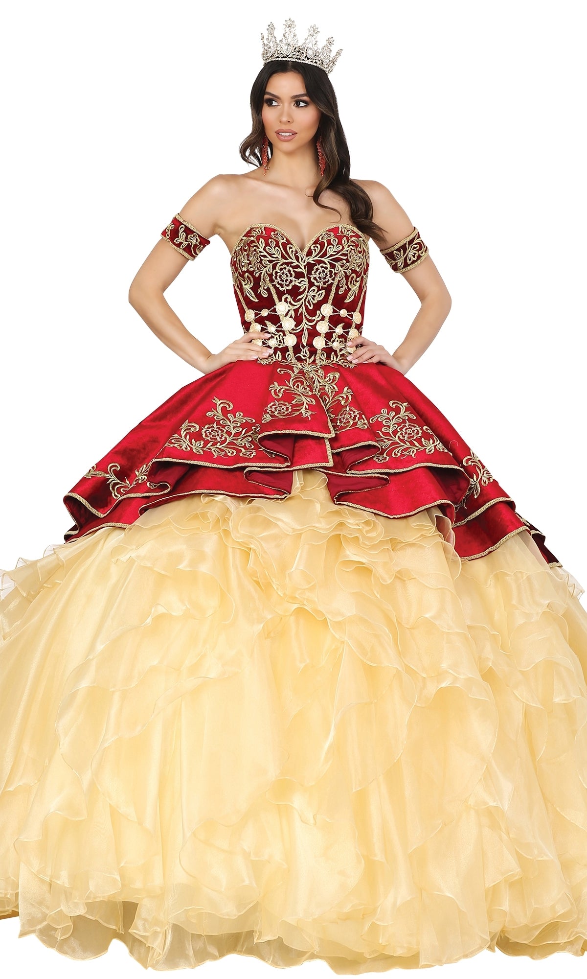 Woman wearing the Quinceanera Dress 1529 by Dancing Queen—a gold and red ball gown with ornate embroidery and a sweetheart strapless neckline—stands hands on hips with a jeweled crown against a white background.